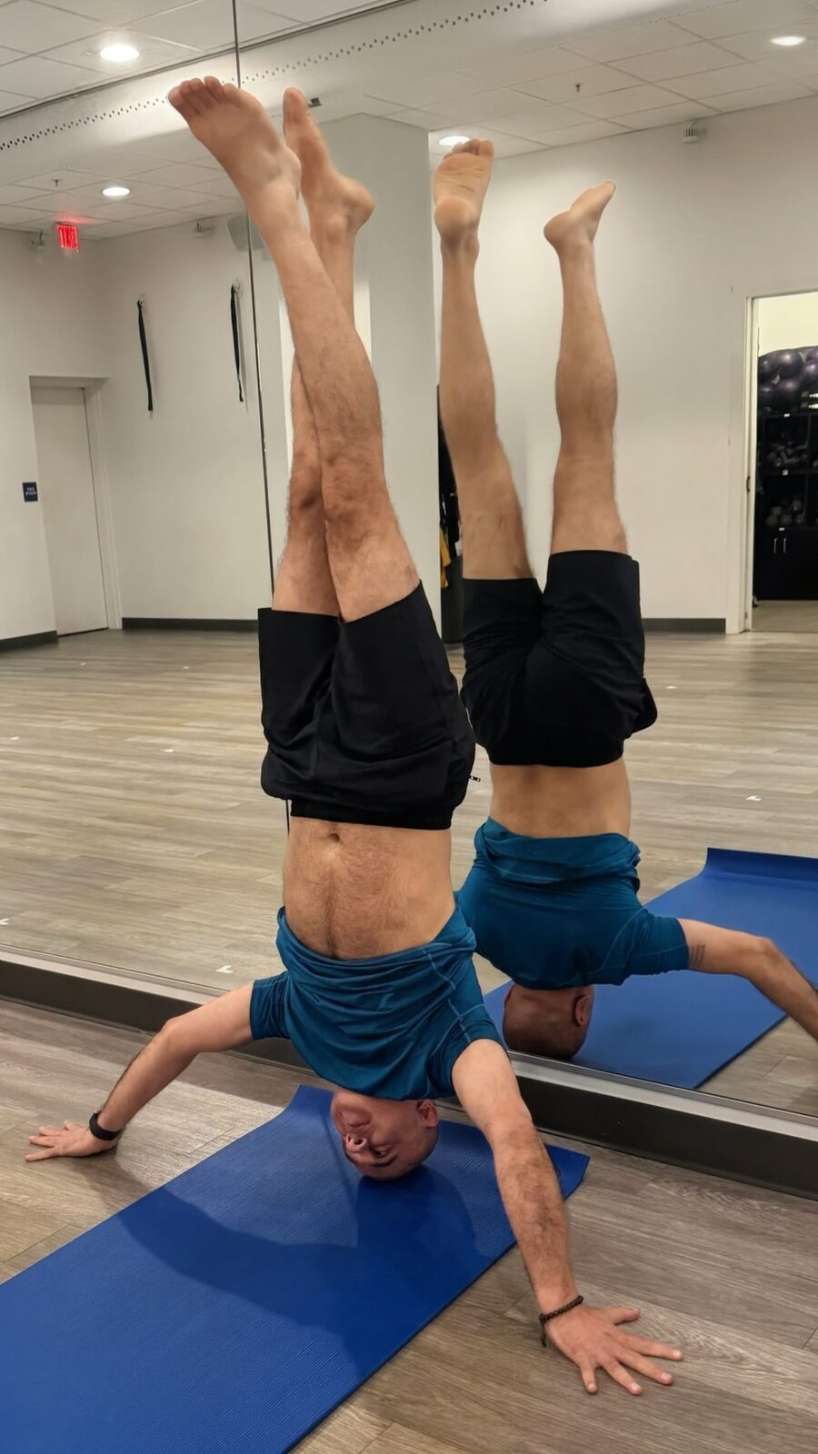 Raj in tripod headstand with legs in a wide split